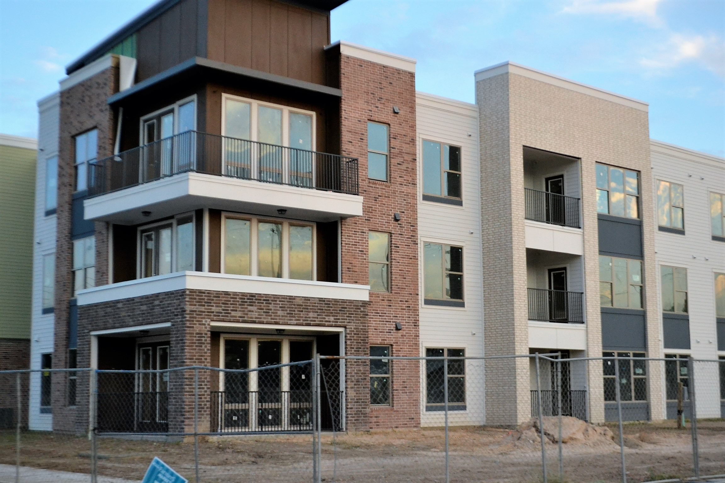 Partially constructed industrial building with construction fence in front.