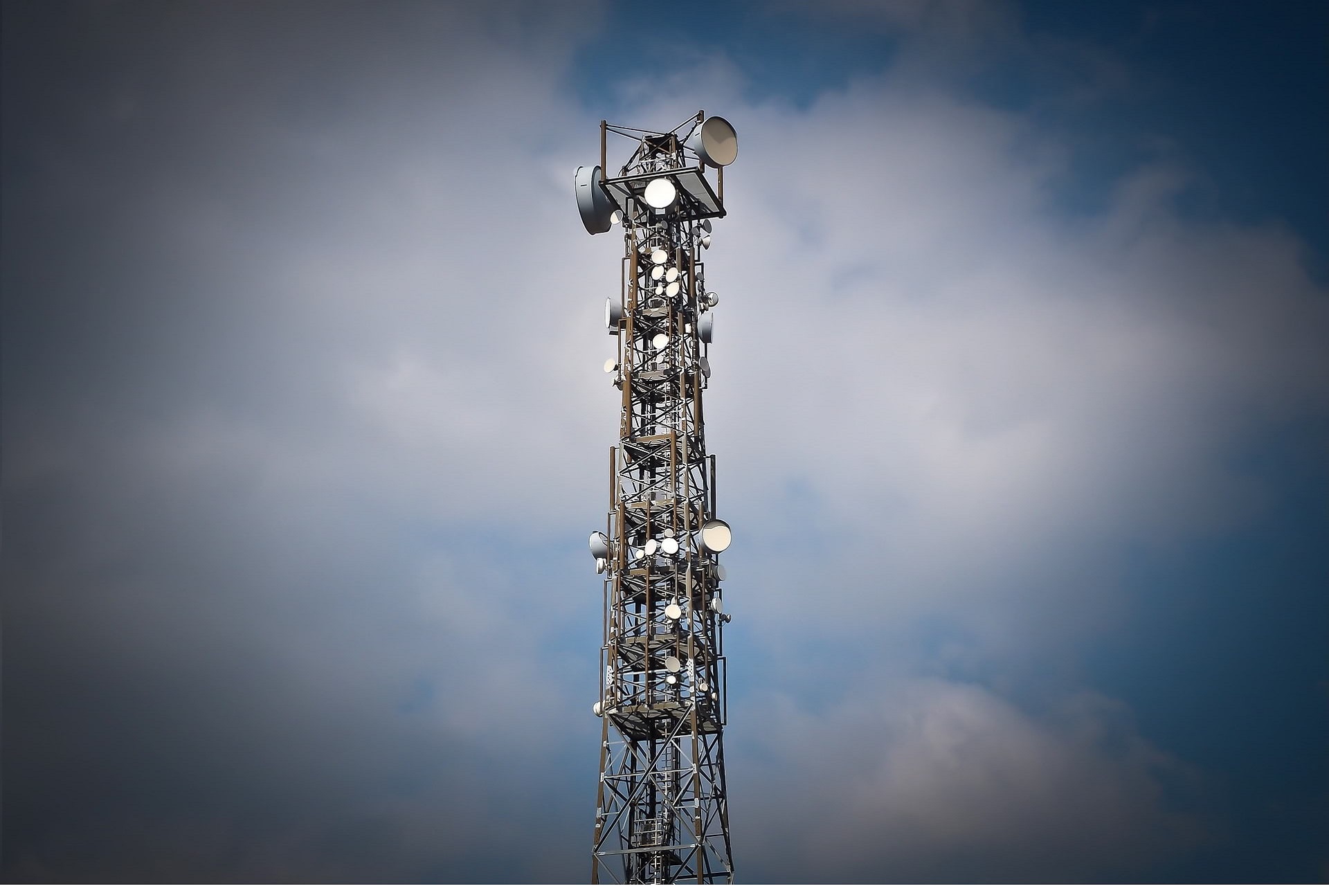 Communications tower against cloudy blue sky.